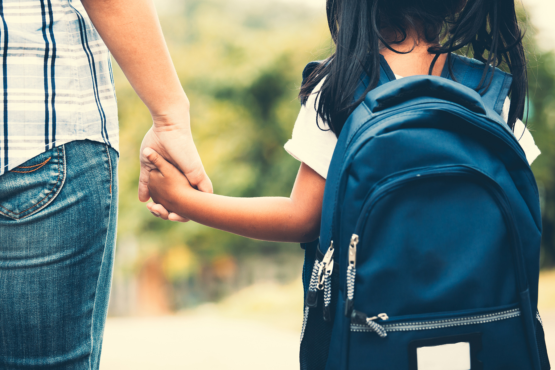 Girl in backpack holding adult hand 