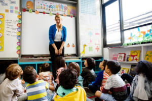 Young students sitting on the floor listening to teacher